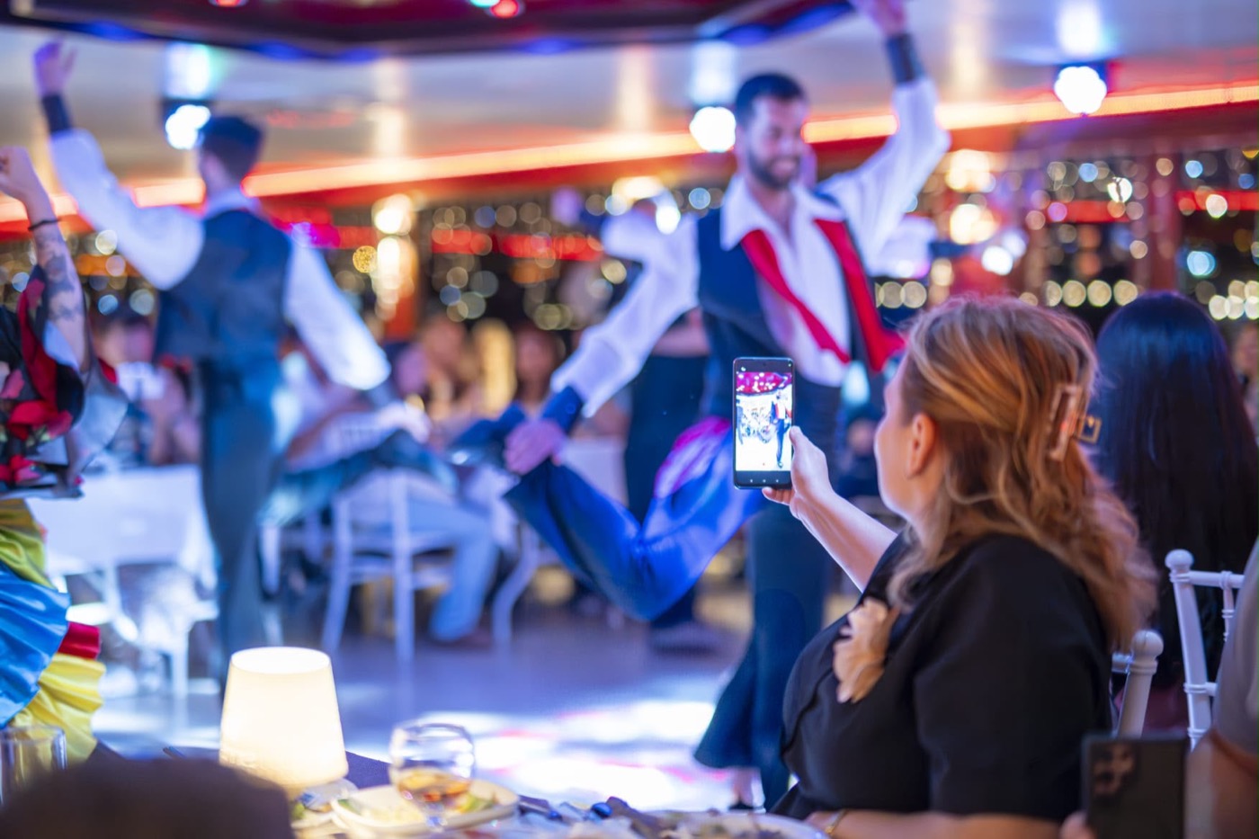 Passageiros assistindo e filmando o show a bordo do Dinner Cruise